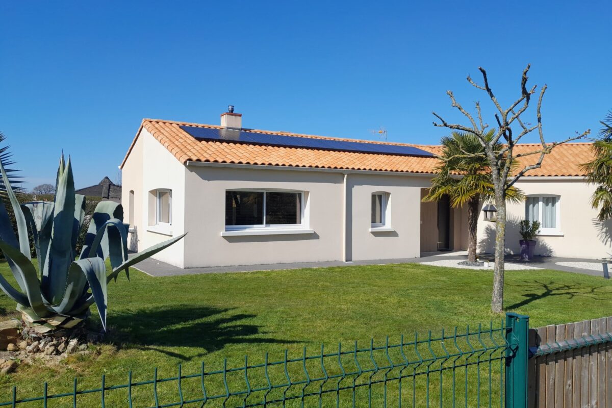 Maison moderne avec jardin et panneaux solaires.